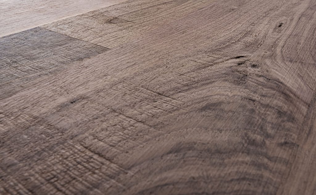 Walnut hardwood flooring with skip band and wire brush texture close up.